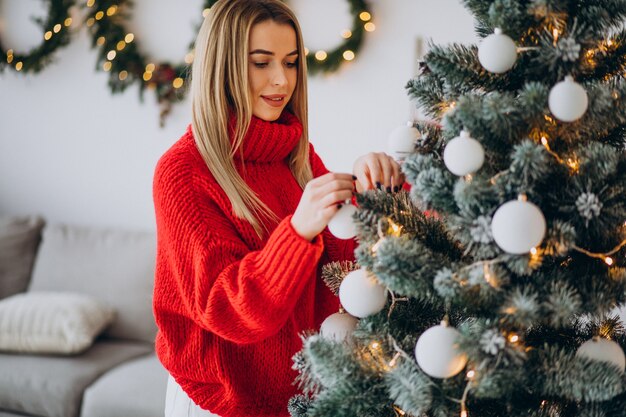 Giovane donna che decora l'albero di Natale