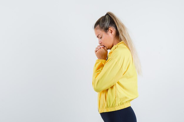 Giovane donna che desidera in impermeabile giallo e sembra speranzosa.