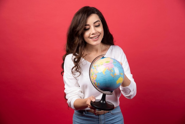 Giovane donna che esamina felicemente il globo. Foto di alta qualità