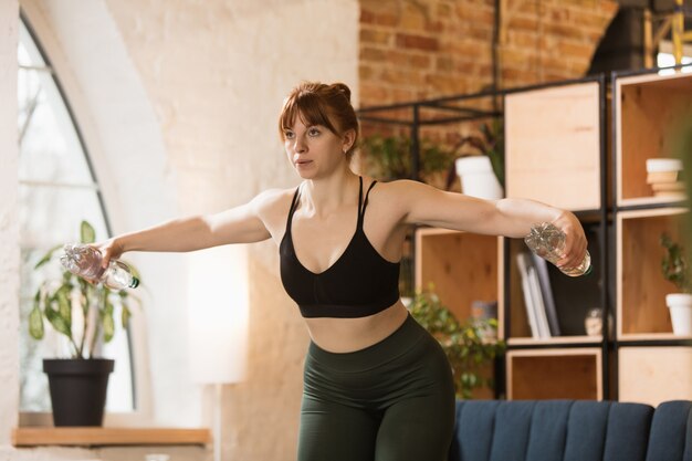 Giovane donna che esercita yoga aerobico fitness a casa stile di vita sportivo che si attiva durante il blocco