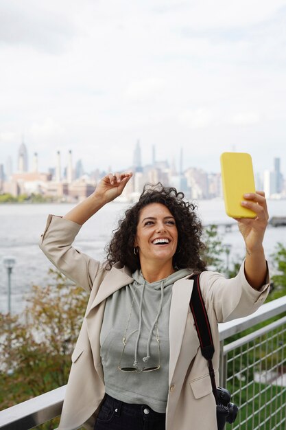 Giovane donna che esplora la città mentre prende selfie con lo smartphone