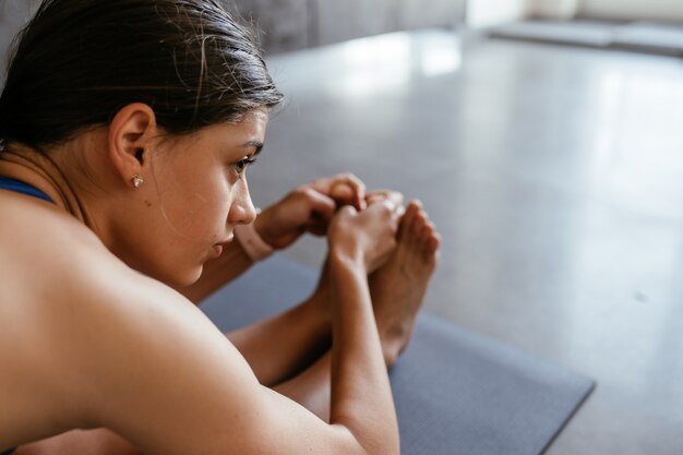 Giovane donna che fa esercizio di posa di yoga a casa, stile di vita sano