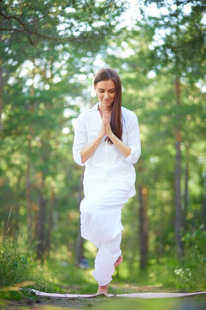 Giovane donna che fa lezione di yoga nel parco