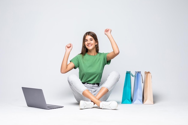 Giovane donna che fa shopping online a casa seduta accanto alla fila di borse della spesa