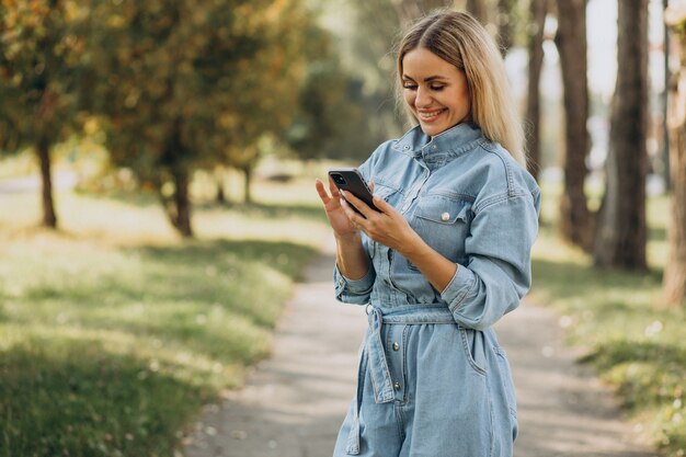 Giovane donna che fa shopping online nel parco