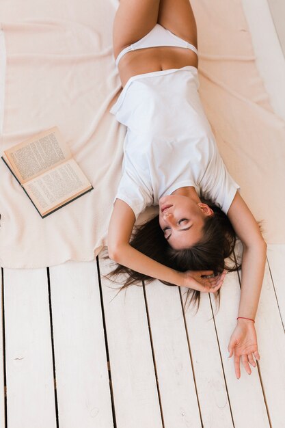 Giovane donna che fa un sonnellino vicino al libro