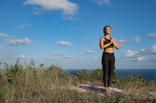 Giovane donna che fa yoga all'aperto con incredibile vista posteriore. Bali. Indonesia.