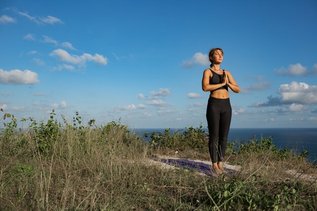 Giovane donna che fa yoga all'aperto con incredibile vista posteriore. Bali. Indonesia.