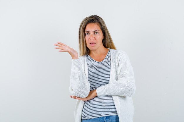 Giovane donna che finge di mostrare qualcosa in t-shirt, giacca e sembra confusa. vista frontale.