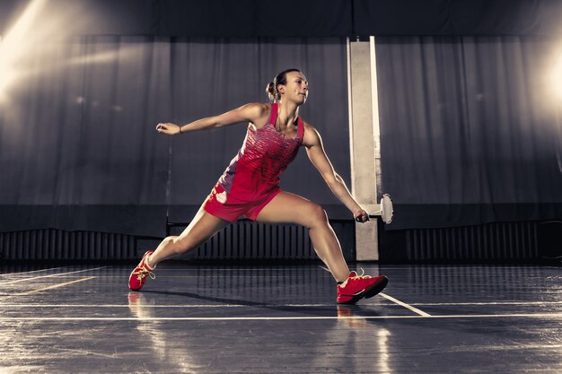 Giovane donna che gioca a badminton in palestra