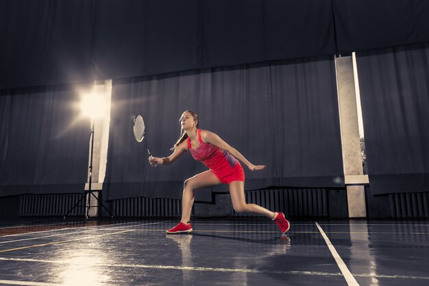 Giovane donna che gioca a badminton in palestra