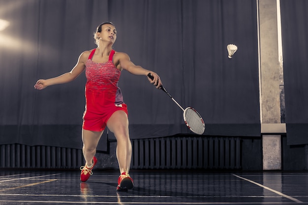 Giovane donna che gioca a badminton in palestra