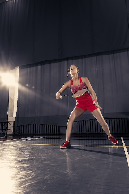 Giovane donna che gioca a badminton in palestra