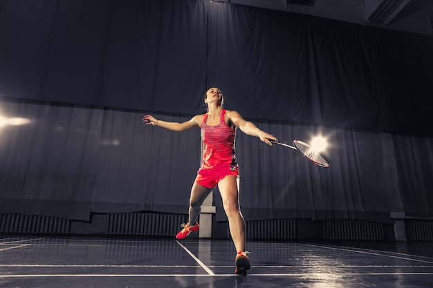 Giovane donna che gioca a badminton in palestra