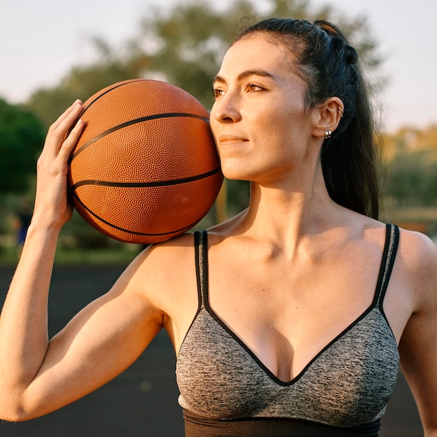 Giovane donna che gioca a basket da solo