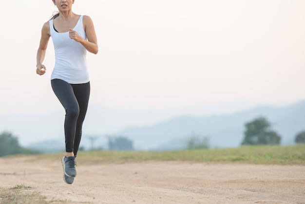 Giovane donna che gode di uno stile di vita sano mentre fa jogging lungo una strada di campagna