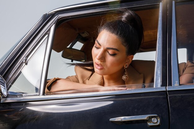 Giovane donna che guarda dal finestrino dell'auto classica