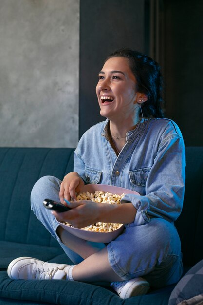 Giovane donna che guarda il servizio di streaming a casa