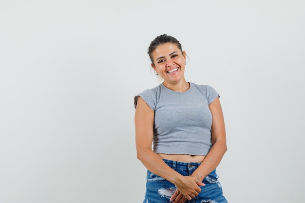 Giovane donna che guarda l'obbiettivo in t-shirt, pantaloncini e sembra gioiosa.