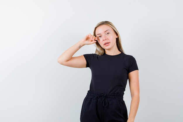 Giovane donna che guarda l'obbiettivo mentre posa in t-shirt, pantaloni e sembra seducente. vista frontale.