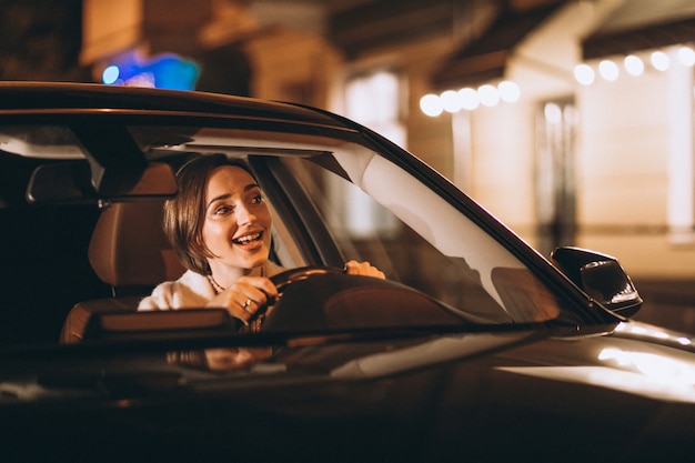 Giovane donna che guida in auto di notte