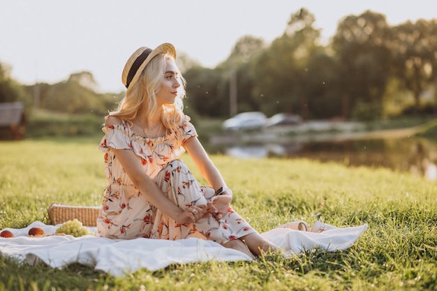 Giovane donna che ha picnic nel parco