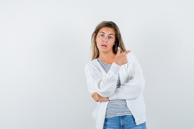 Giovane donna che indica il lato destro in t-shirt, giacca e sguardo esitante, vista frontale.