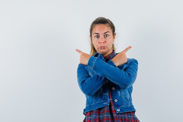 Giovane donna che indica lontano in camicia, giacca e guardando pensieroso. vista frontale.