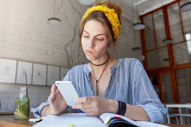 Giovane donna che indossa bandana e studia nella caffetteria