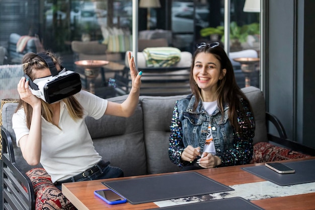 Giovane donna che indossa il set Vr e fa un gesto alla fermata dell'amica