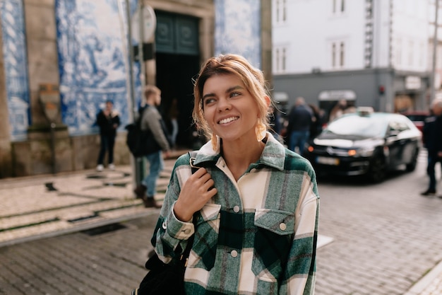 Giovane donna che indossa la camicia in denim camminando per la strada della città