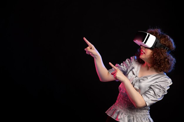Giovane donna che indossa le cuffie da realtà virtuale sulla superficie scura