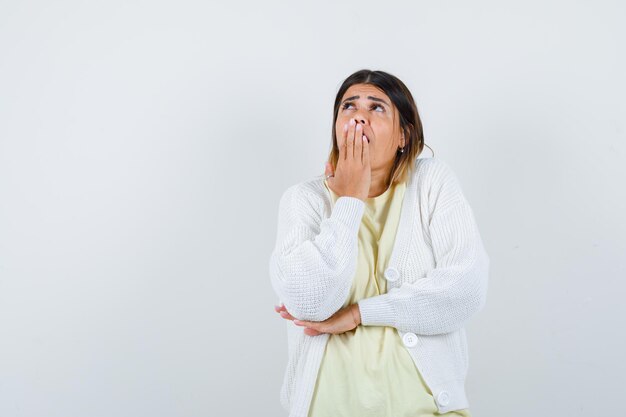 Giovane donna che indossa un cardigan bianco che sbadiglia