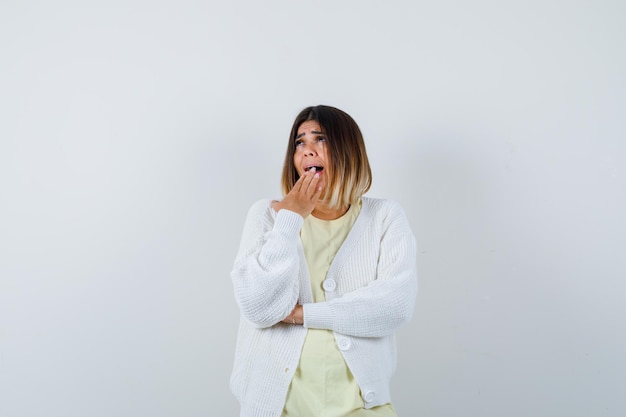 Giovane donna che indossa un cardigan bianco che sbadiglia