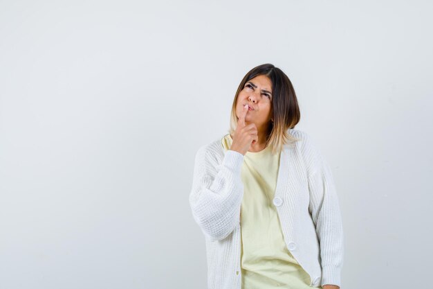 Giovane donna che indossa un cardigan bianco pensando