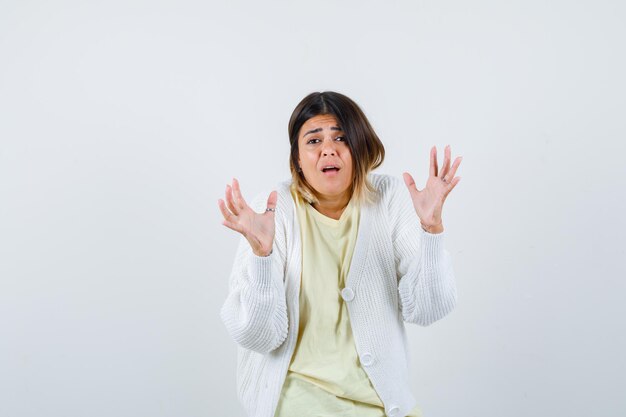 Giovane donna che indossa un cardigan bianco spaventata