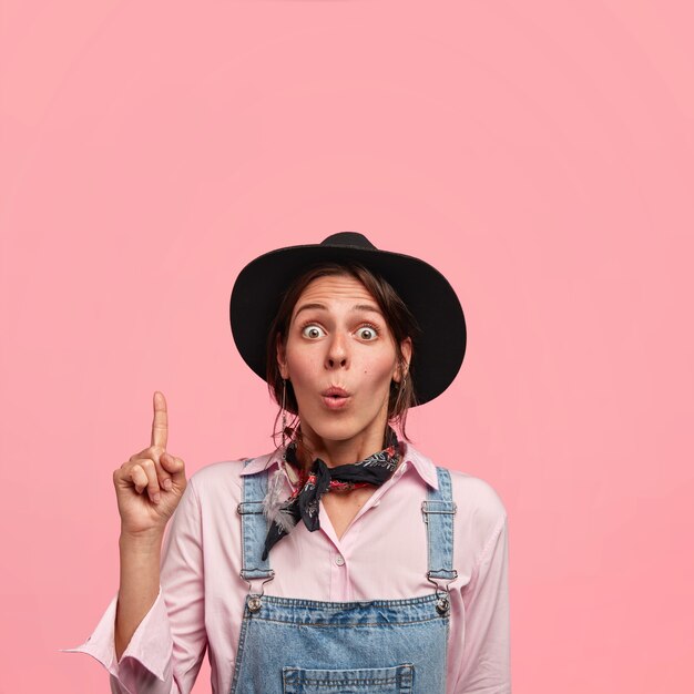 Giovane donna che indossa un grande cappello e tute di jeans