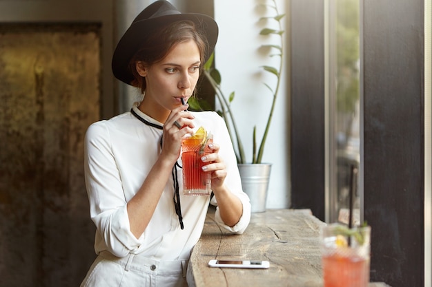 Giovane donna che indossa un grande cappello nella caffetteria