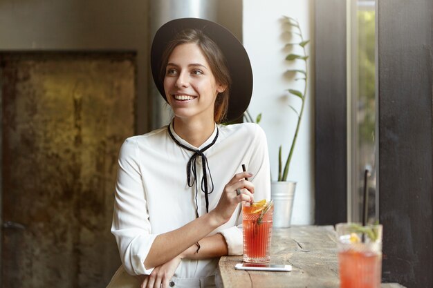 Giovane donna che indossa un grande cappello nella caffetteria