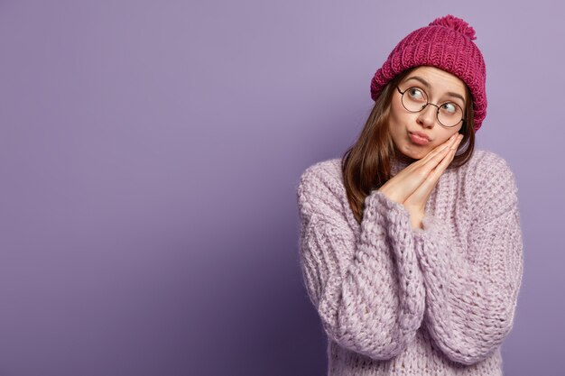 Giovane donna che indossa un maglione viola e cappello