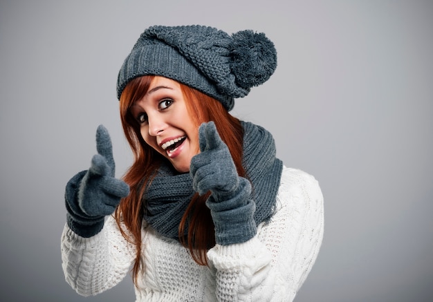 Giovane donna che indossa vestiti caldi che punta alla telecamera