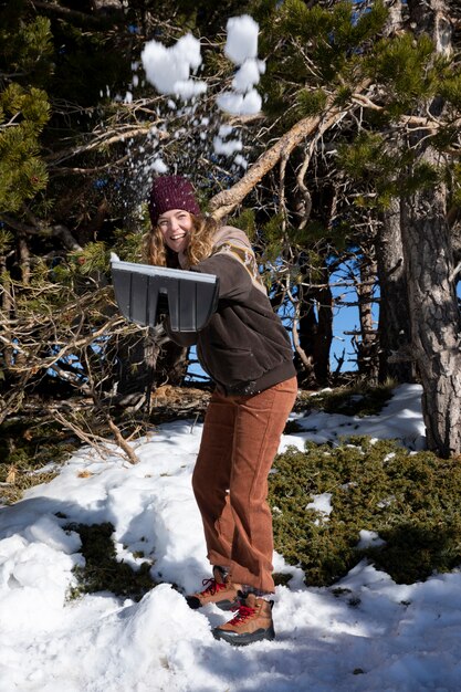 Giovane donna che lancia neve con una pala durante il viaggio invernale