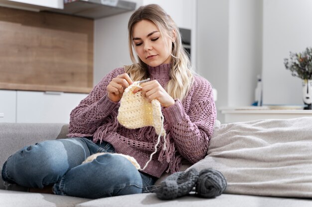 Giovane donna che lavora a maglia mentre ci si rilassa