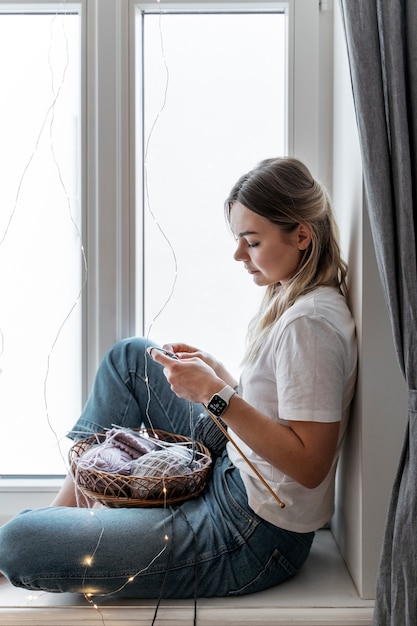 Giovane donna che lavora a maglia mentre ci si rilassa