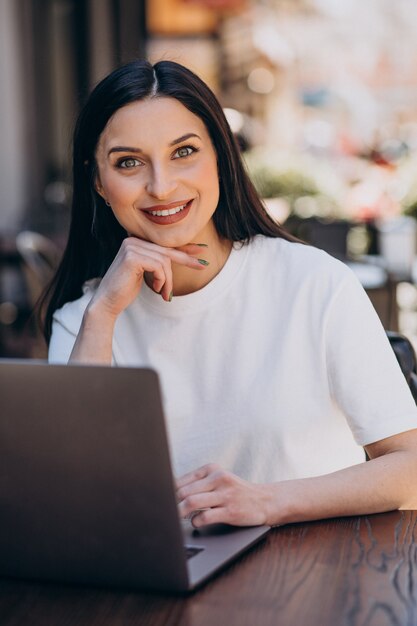 Giovane donna che lavora al computer portatile in un caffè