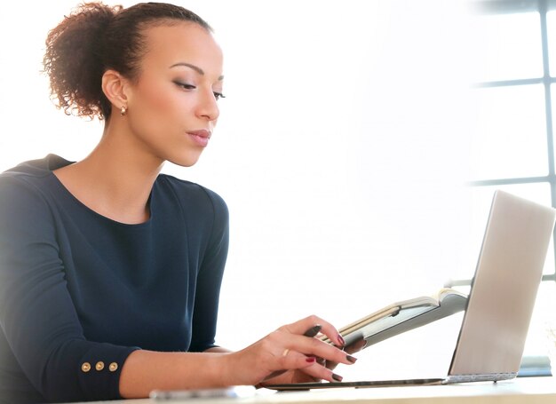 Giovane donna che lavora con il computer portatile e l'agenda