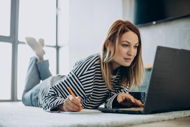 Giovane donna che lavora e studia sul suo computer portatile da casa