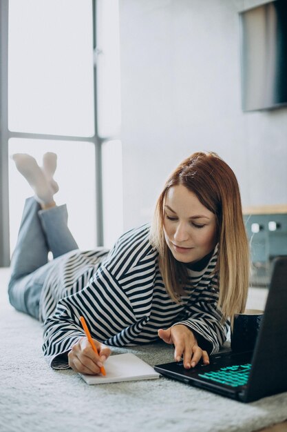 Giovane donna che lavora e studia sul suo computer portatile da casa