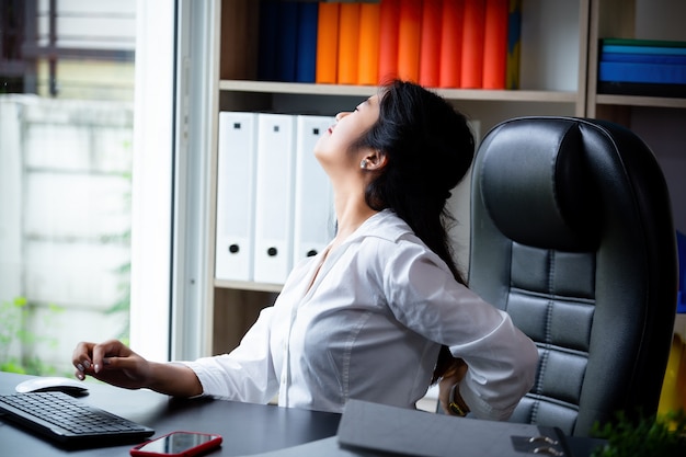 Giovane donna che lavora mal di schiena mentre il lavoro