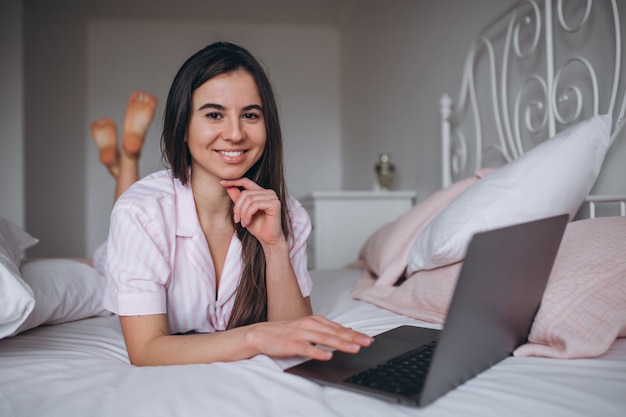 Giovane donna che lavora sul computer a letto